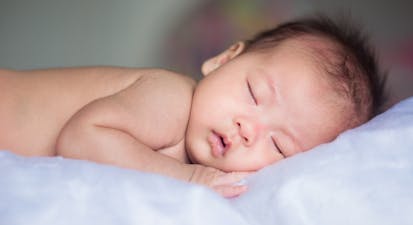 Asian baby sleeping on bluish white blanket