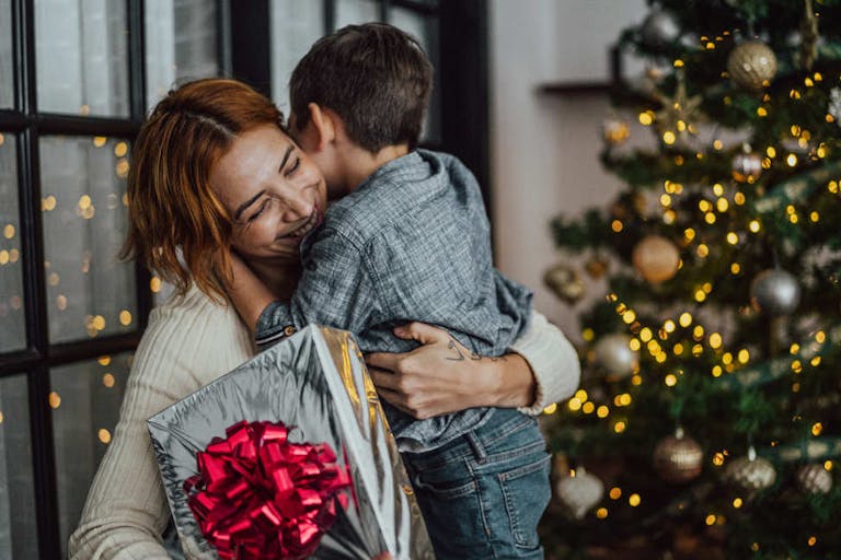 Mother giving Christmas gifts to son at the home