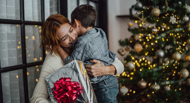 Mother giving Christmas gifts to son at the home