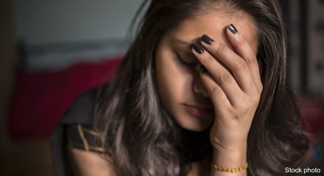 indoor image of sad, depressed young girl feeling headache and thinking by holding her head and looking down at home. (Getty Images) Indian teen sad, abortion trauma