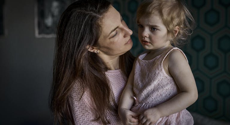 Mother consoling sad toddler girl at home
