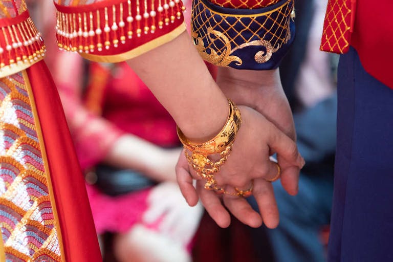 A newlywed Chinese couple in traditional Chinese wedding dresses holding hands