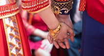 A newlywed Chinese couple in traditional Chinese wedding dresses holding hands