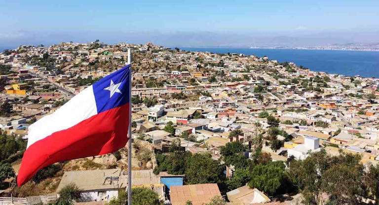 High Angle Shot Of Chile Flag Against Townscape Against Blue Sky