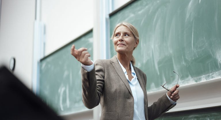 Businesswoman giving presentation by chalkboard at convention center