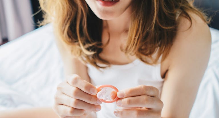 Cropped shot view of woman holding a small condom on her hand before using it with her partner.