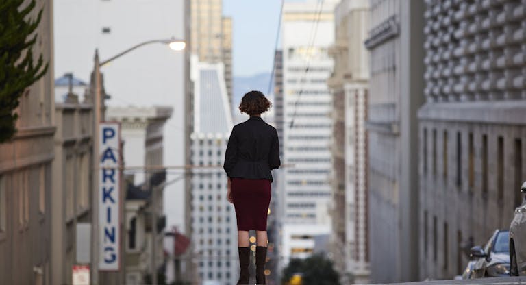 Businesswoman standing on top of steep San Francisco street and looking out