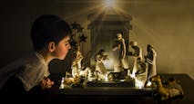 Young boy leaning in looking closely at a ceramic nativity scene.