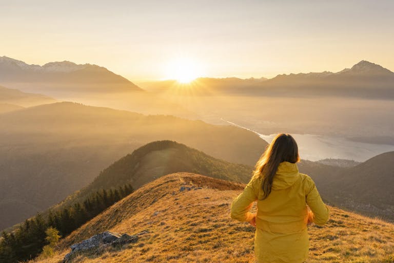 Woman gazing at Lake Como and mountains from high up, Italy.