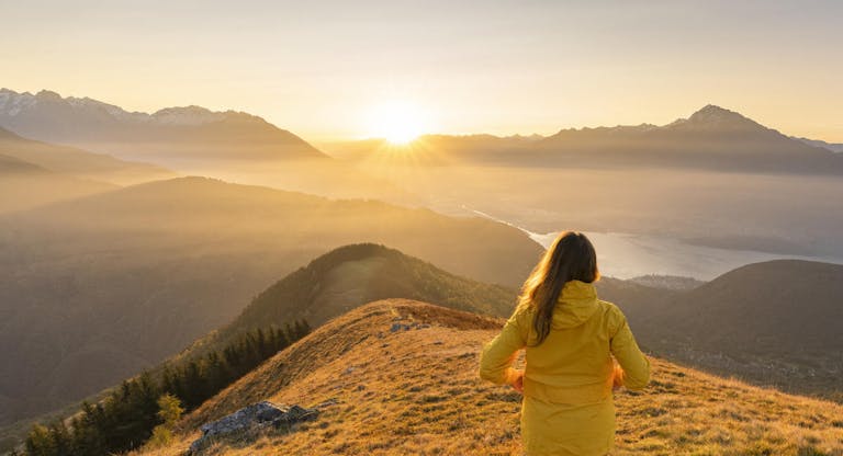 Woman gazing at Lake Como and mountains from high up, Italy.
