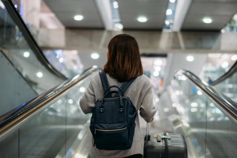 Young woman holding suitcase or baggage with backpack in the international airport.