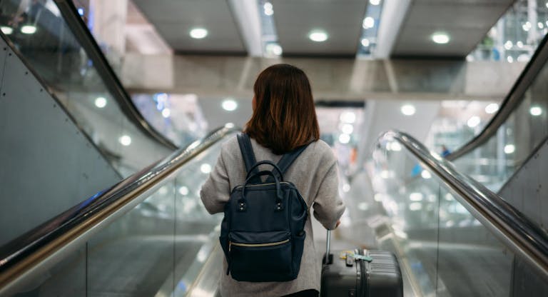 Young woman holding suitcase or baggage with backpack in the international airport.