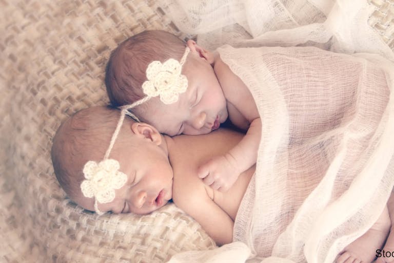 Cuddling newborn twin sisters