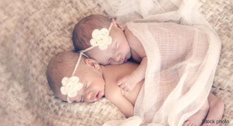 Cuddling newborn twin sisters
