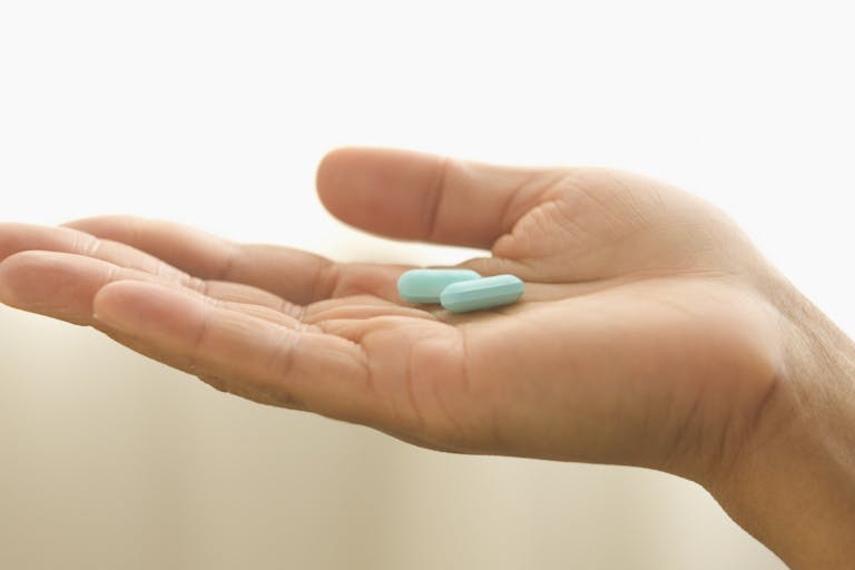 Close up of hand holding pills Australian man nearly killed by partner’s assisted suicide drugs featured image