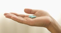 close up of hand holding blue-green pills