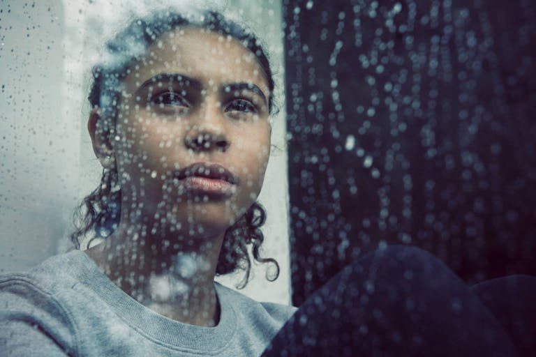 Girl staring out of rainy window