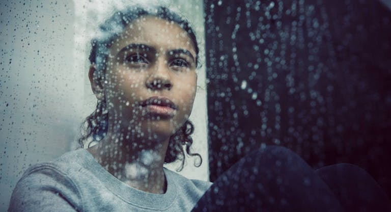Girl staring out of rainy window