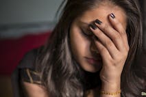 Photo: Bhupi/Getty Images indoor image of sad, depressed young girl feeling headache and thinking by holding her head and looking down at home.