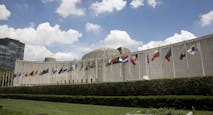 Flags and concrete building above grass and shrubs