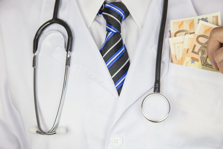 Greedy doctor squeezing money. Medical concept