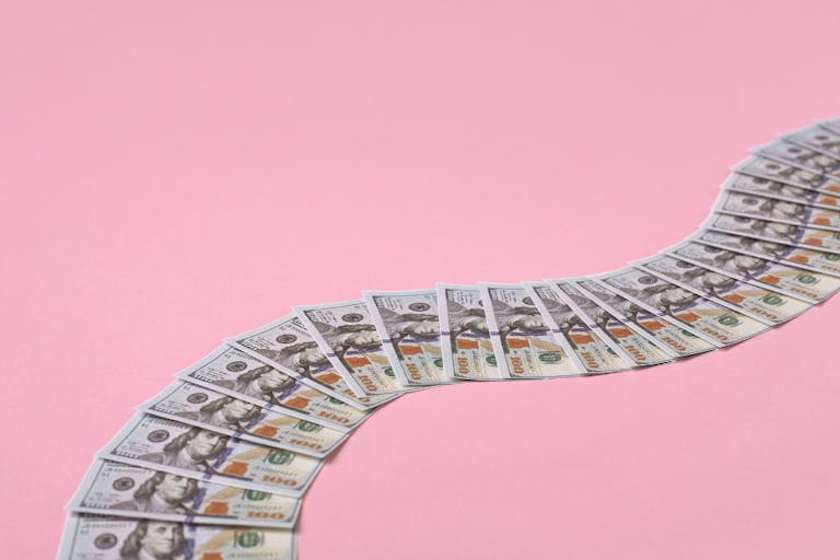 Money path made of 100 dollar bills on pink background with copy space.