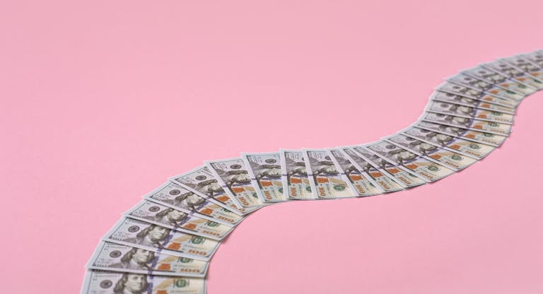 Money path made of 100 dollar bills on pink background with copy space.