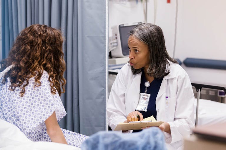 Teen girl listens as emergency room doctor asks questions