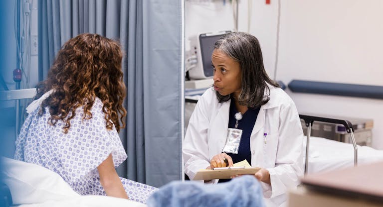 Teen girl listens as emergency room doctor asks questions