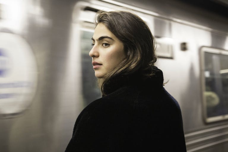 Train arriving at station while woman waits