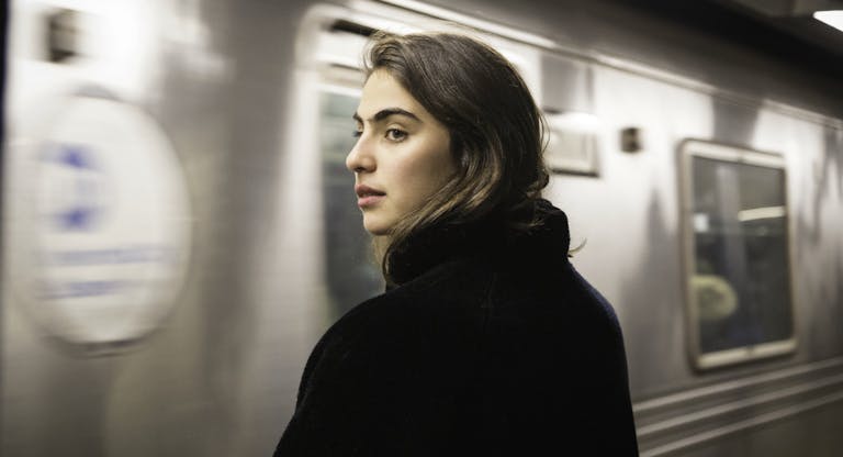 Train arriving at station while woman waits