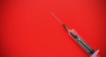 Bullet in a disposable syringe on a red background