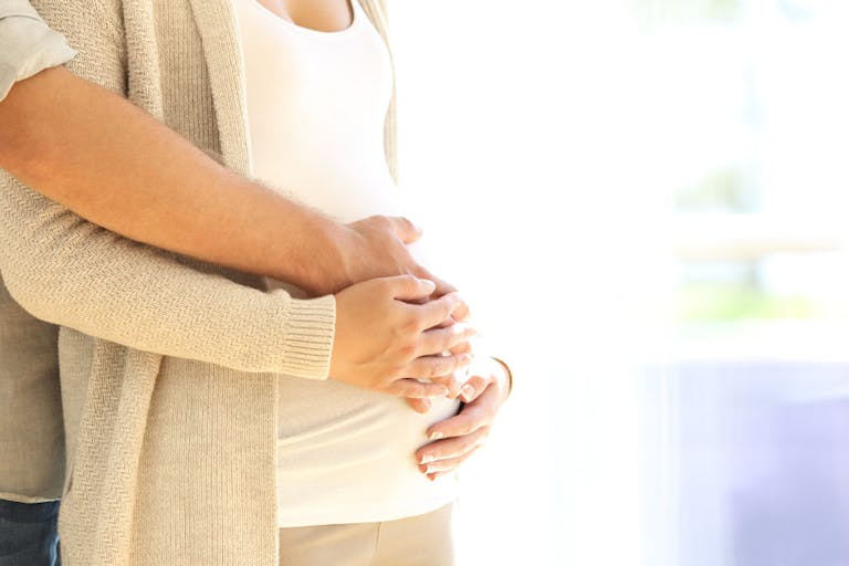 Close up of parents hands touching pregnant belly