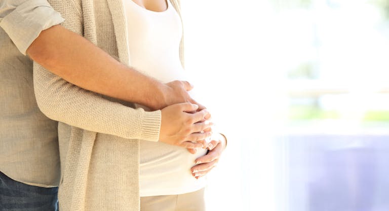 Close up of parents hands touching pregnant belly