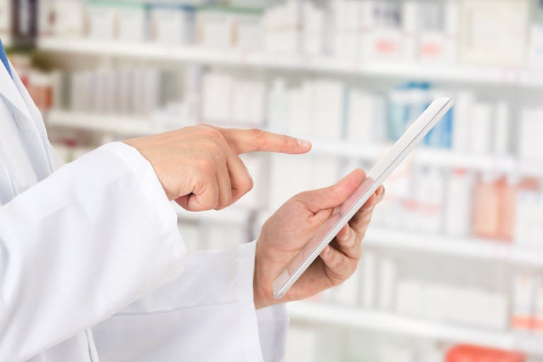 Pharmacist making notes on a digital tablet