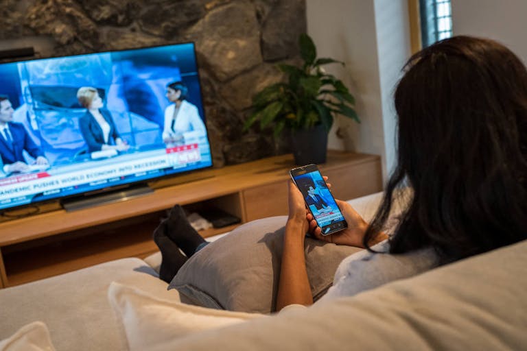 Woman sitting in living room and watching news broadcast