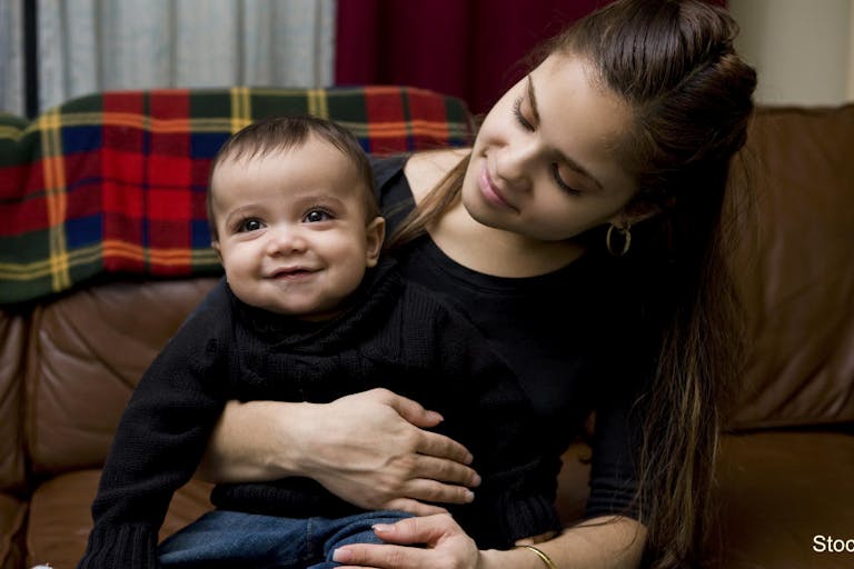 Adorable Baby Boy Sitting on Latina Mother’s Lap at Home