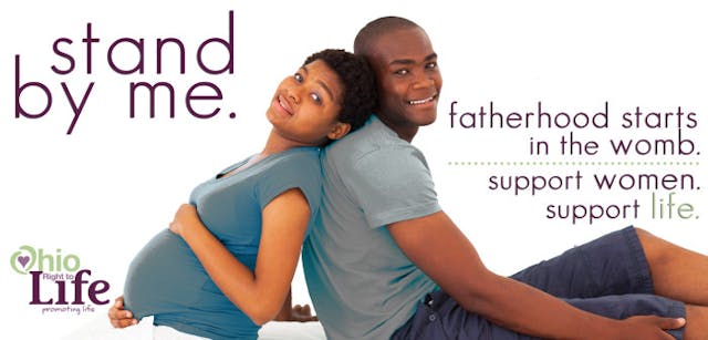 pregnant african woman and husband sitting on bed