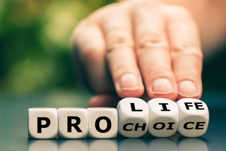 Hand turns dice and changes the expression “pro choice” to “pro life”.