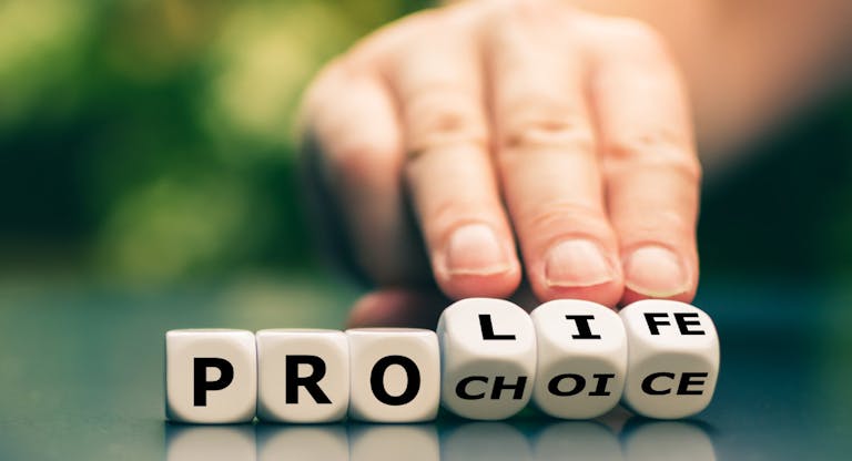 Hand turns dice and changes the expression “pro choice” to “pro life”.