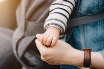 Close up of mother carrying baby and holding hand