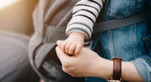 Close up of mother carrying baby and holding hand