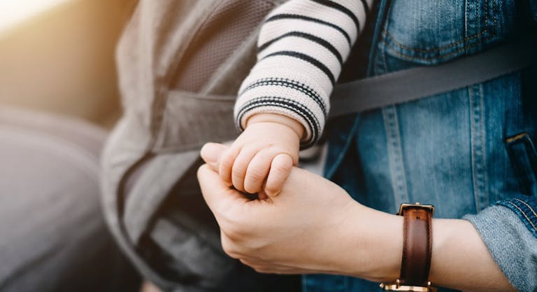 Close up of mother carrying baby and holding hand