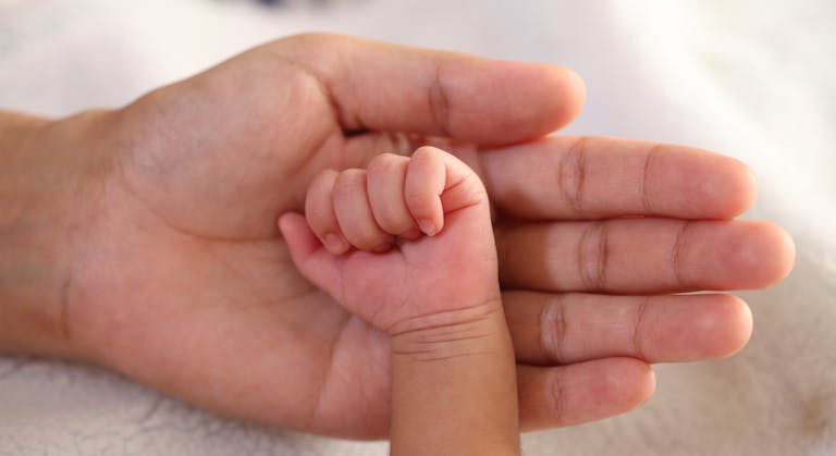Newborn baby hand in parents hand