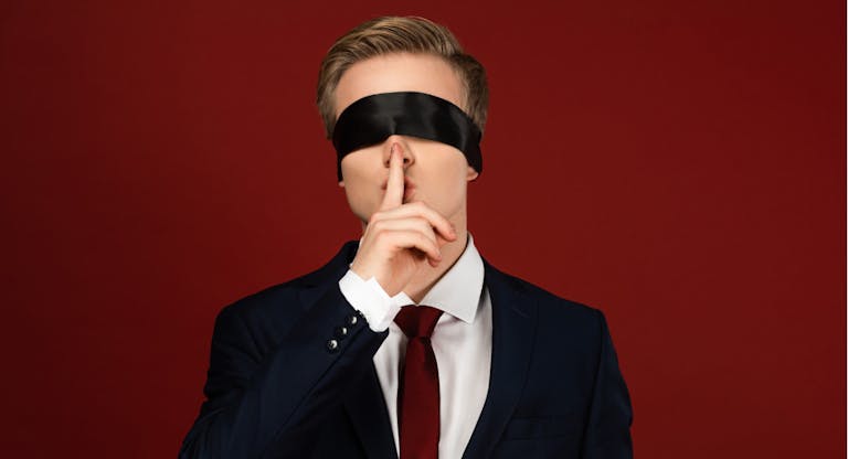 man imitating politician with blindfold on eyes showing shh gesture on red background