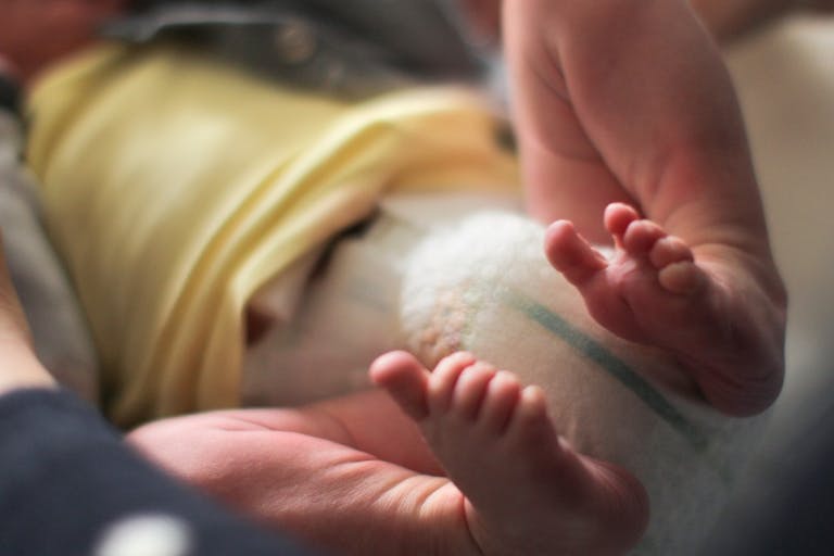 a Mother changing her newborn baby’s diaper for the first time at home.