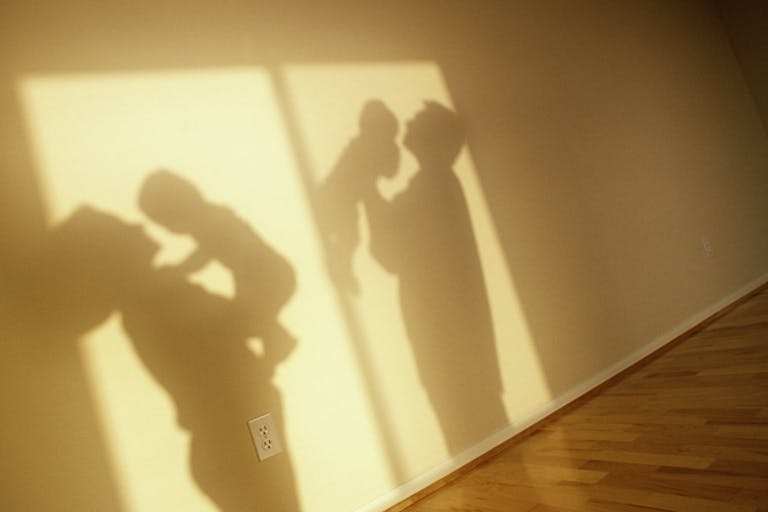 SHADOWS OF PARENTS HOLDING BABIES IN EMPTY ROOM