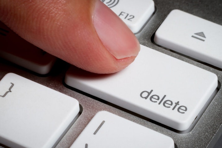 Closeup of finger on delete key in a keyboard.