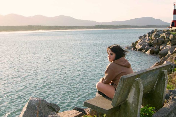 Girl sitting on bench by sea