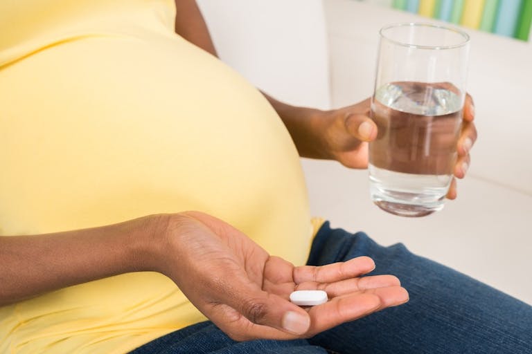 Pregnant Woman Taking Medicine At Home